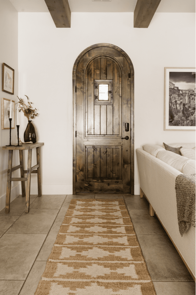 styleberry-creative-interiors-san-antonio-tx-earth-tones-living-room-reveal-arched-wooden-door-with-runner-organic-home-renovation